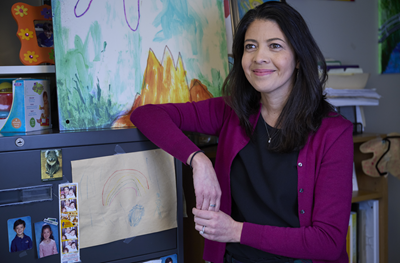 Melanie Pellecchia places her arm on a cabinet, decorated with children's drawings.